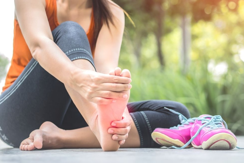 A woman sat down, took off her shoes, and massaged one foot as she felt pain.