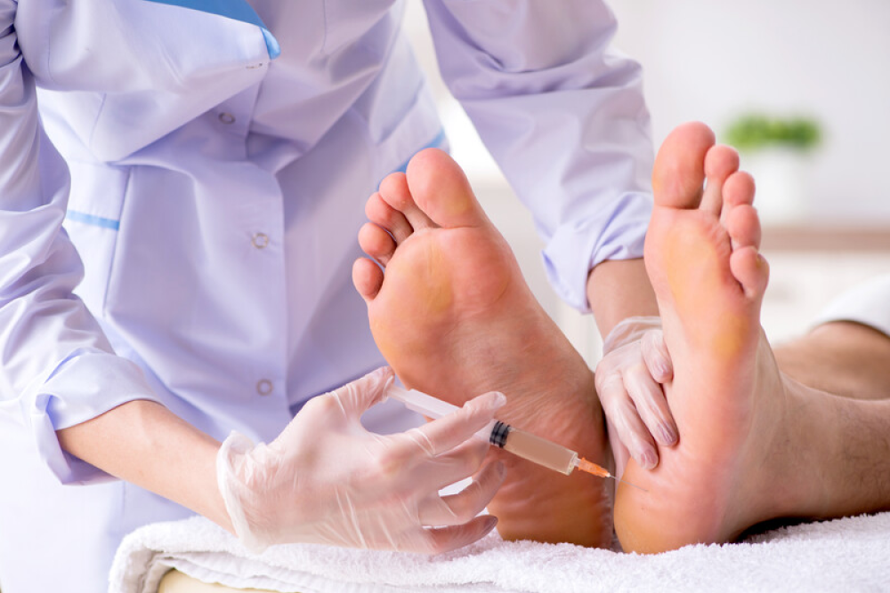 A podiatrist injects patients' feet in order to cure the illness.