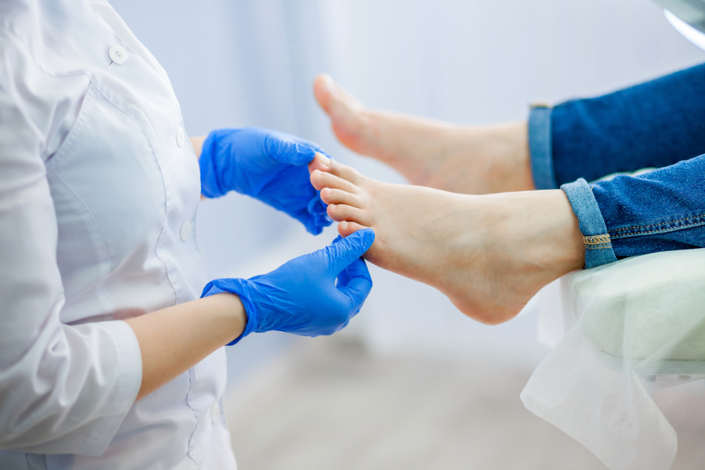 A podiatrist examines her patient's foot while touching the big and little toes.