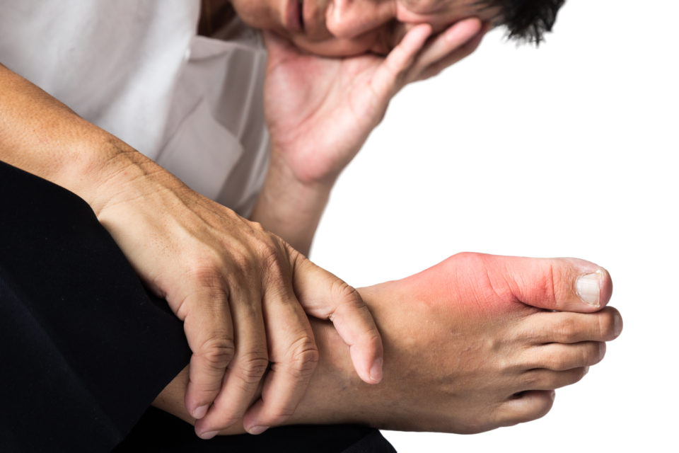 A man is sitting, having problems with his one foot caused by bunions.