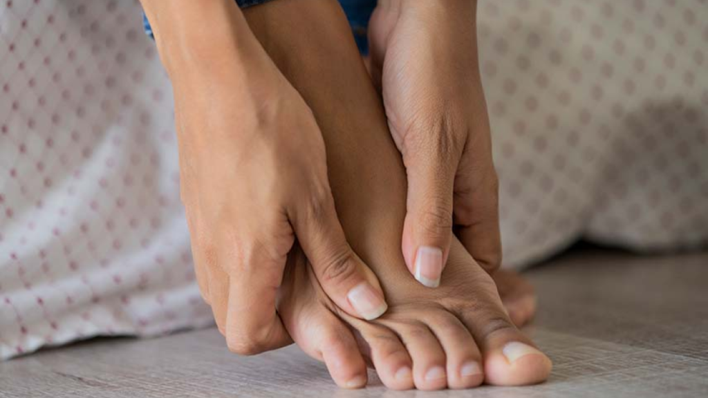 A woman massage her foot because she feels bothered by her feet.